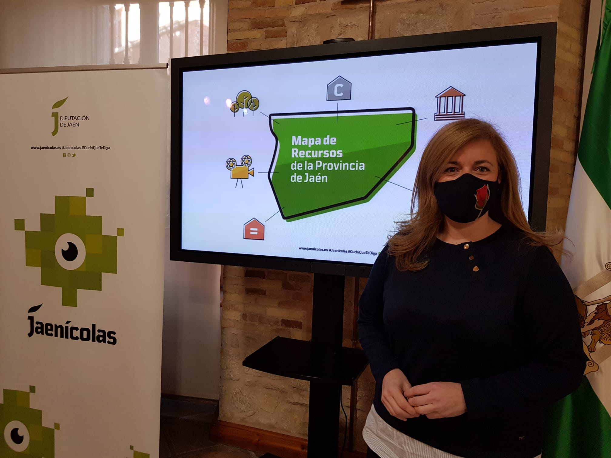 Pilar Lara, con la imagen de este mapa de recursos juveniles detrás. JPG 207 KB | Diputación de Jaén | Ampliar imagen